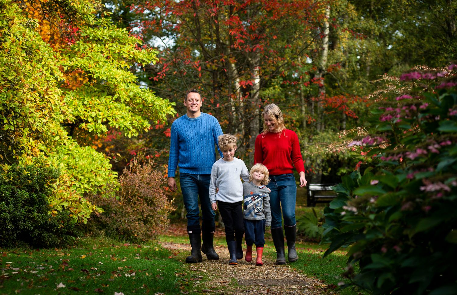 Family walking in autumn Child in welcoming stance at Furzey Gardens