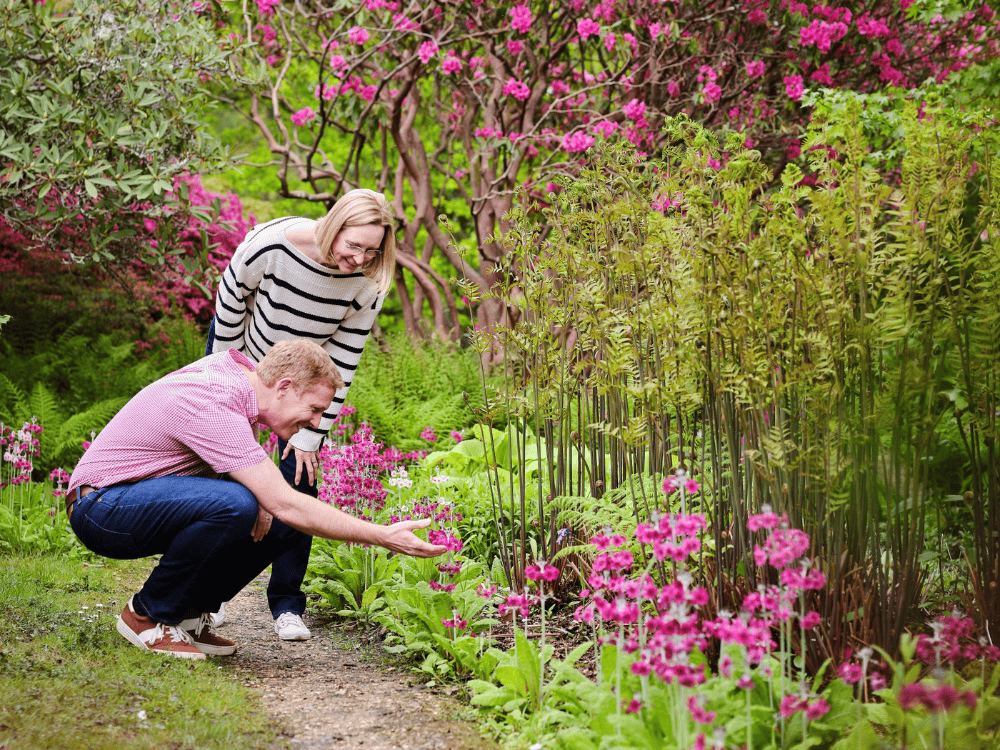 Young man in green top standing in front of hatched structure at Furzey Gardens. 